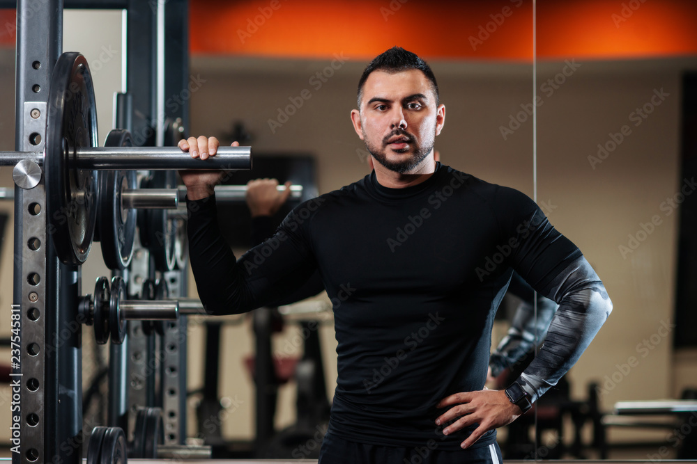Handsome with big muscles posing next to the barbell Handsome with big muscles posing next to the barbell