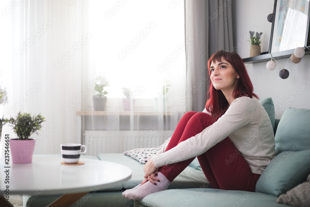 Young woman smiling and thinking about something at home Young woman smiling and thinking about something at home