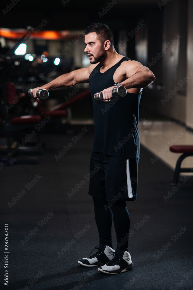 Bodybuilder doing Exercise for the shoulder muscles, deltoid with dumbbell in the gym Bodybuilder doing Exercise for the shoulder muscles, deltoid with dumbbell in the gym