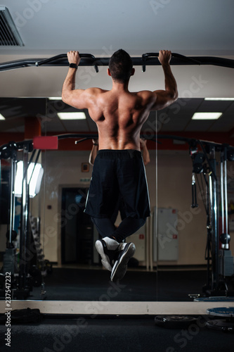 Athletic man making pull-up exercises on a crossbar in the gym