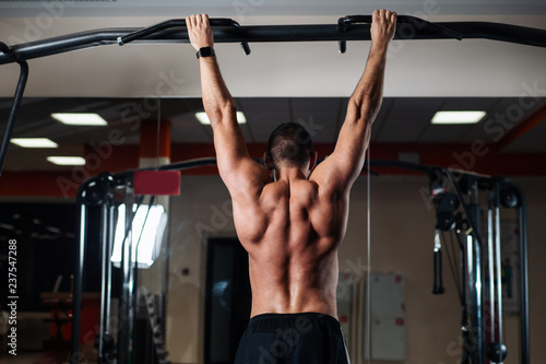 Athletic man making pull-up exercises on a crossbar in the gym