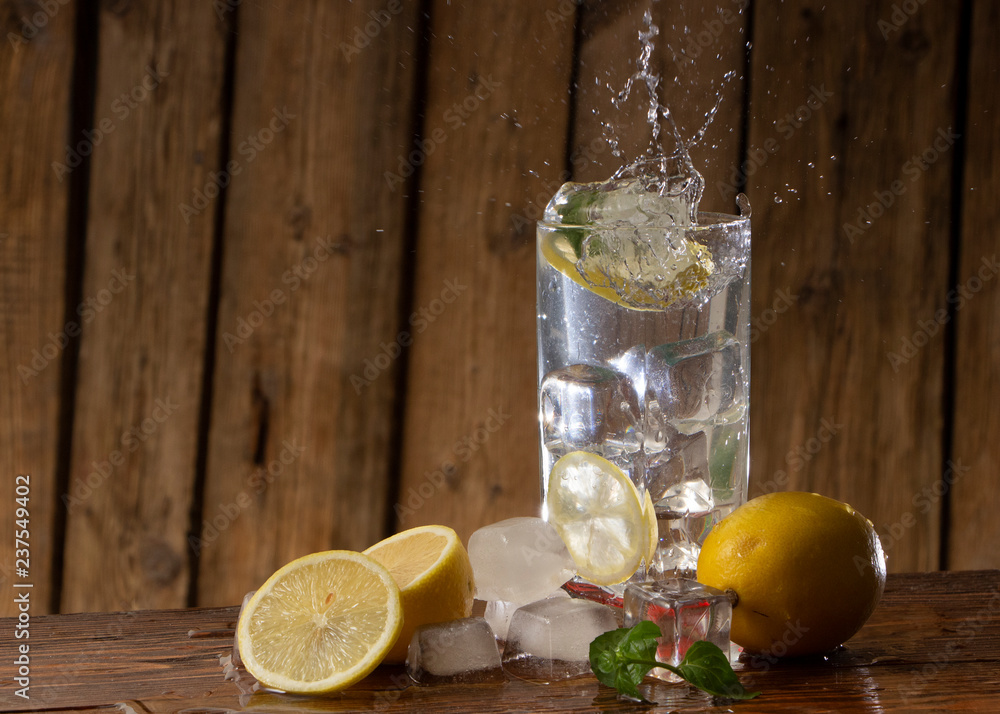 Transparent glass of lemonade on the old wooden table against the background of a wooden wall with shabby boards