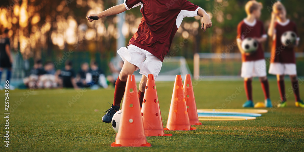 Football Drills: The Slalom Drill. Youth soccer practice drills. Young  football players training on pitch. Soccer slalom cone drill. Boy in red soccer  jersey shirt running with ball between cones Stock Photo