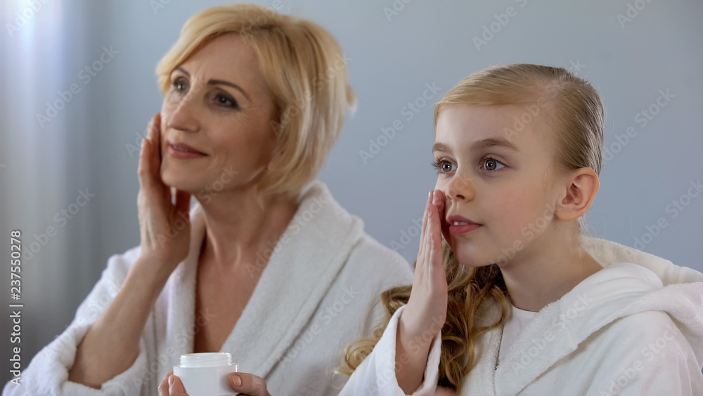 Grandmother and granddaughter applying face cream and smiling, skin care, beauty Grandmother and granddaughter applying face cream and smiling, skin care, beauty