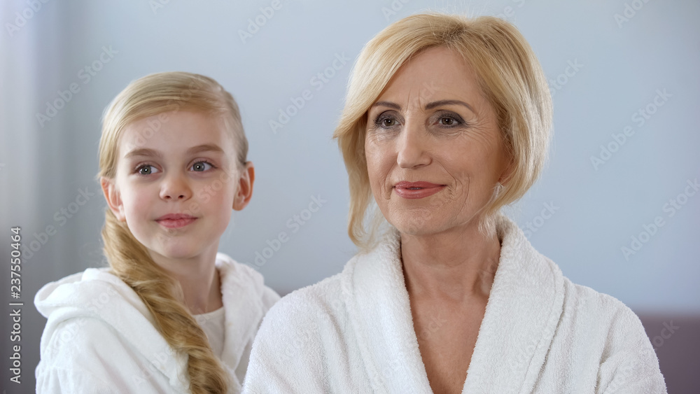 Pretty little girl and grandmother looking in mirror and enjoying their beauty Pretty little girl and grandmother looking in mirror and enjoying their beauty