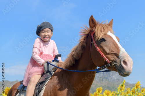 Happy cute girl riding horse in sunflower field © kwanchaichaiudom