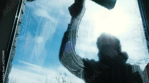 Man lathers the dirty window of himself at home on the balcony close-up photo