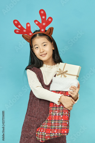 Asian girl with a Christmas concept headdress Child, Close up of cute little asian girl on blue background isolated.