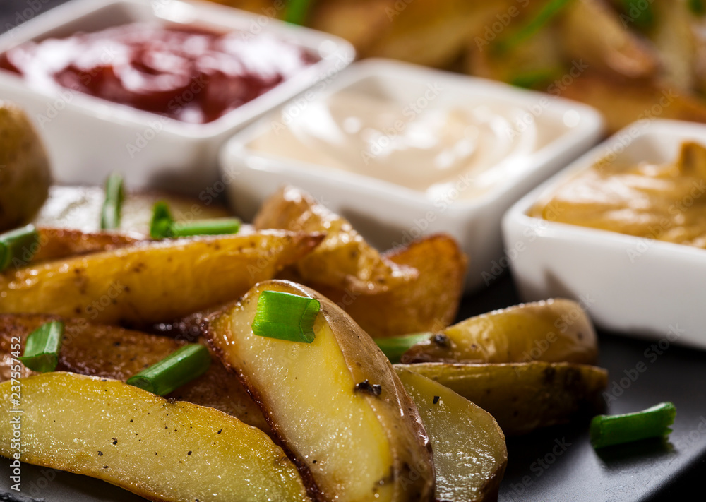 Homemade organic vegetable vegan vegetarian baked potato wedges with chives and sauces. Homemade organic vegetable vegan vegetarian baked potato wedges with chives and sauces.
