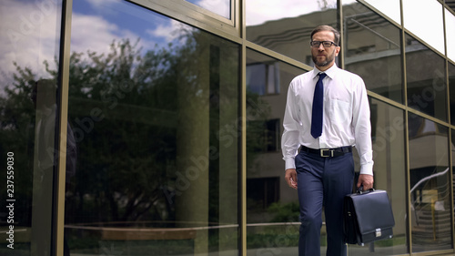 Serious businessman with briefcase going to work, purposeful and successful