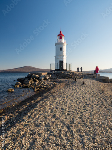 Tokarevsky lighthouse and people in the background of the Russian island of the Far Eastern city of Vladivostok. December, 2018 photo