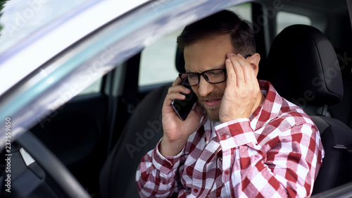 Car driver talking on phone, suffering from strong headache, stressful life