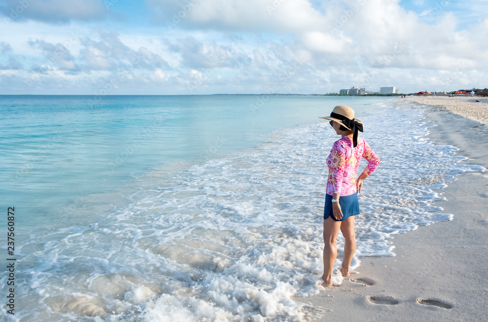 Woman Standing on a Caribbean Beach with a Short Skirt, Colorful Top and Straw Hat