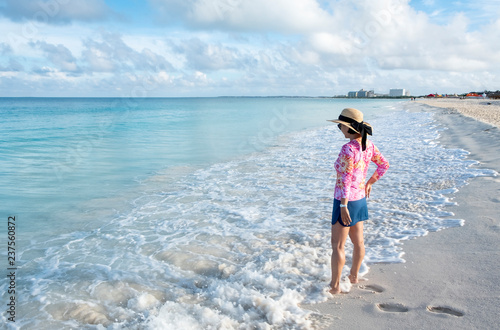 Woman Standing on a Caribbean Beach with a Short Skirt, Colorful Top and Straw Hat