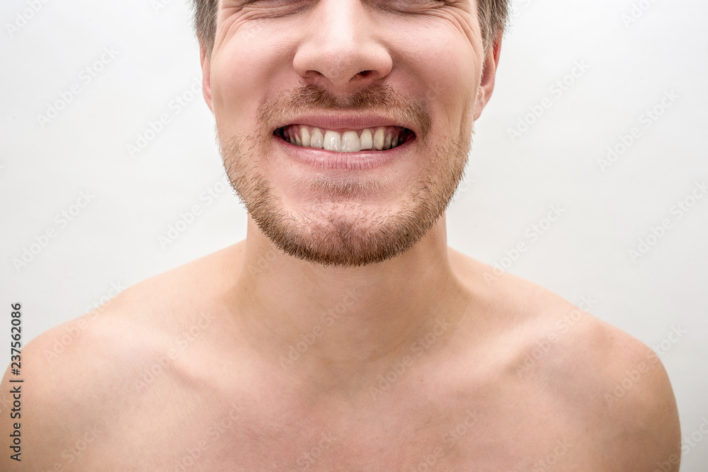 Cut virew of young man smiling. He shows healthy white teeth. Isolated on white baclground. Close up.