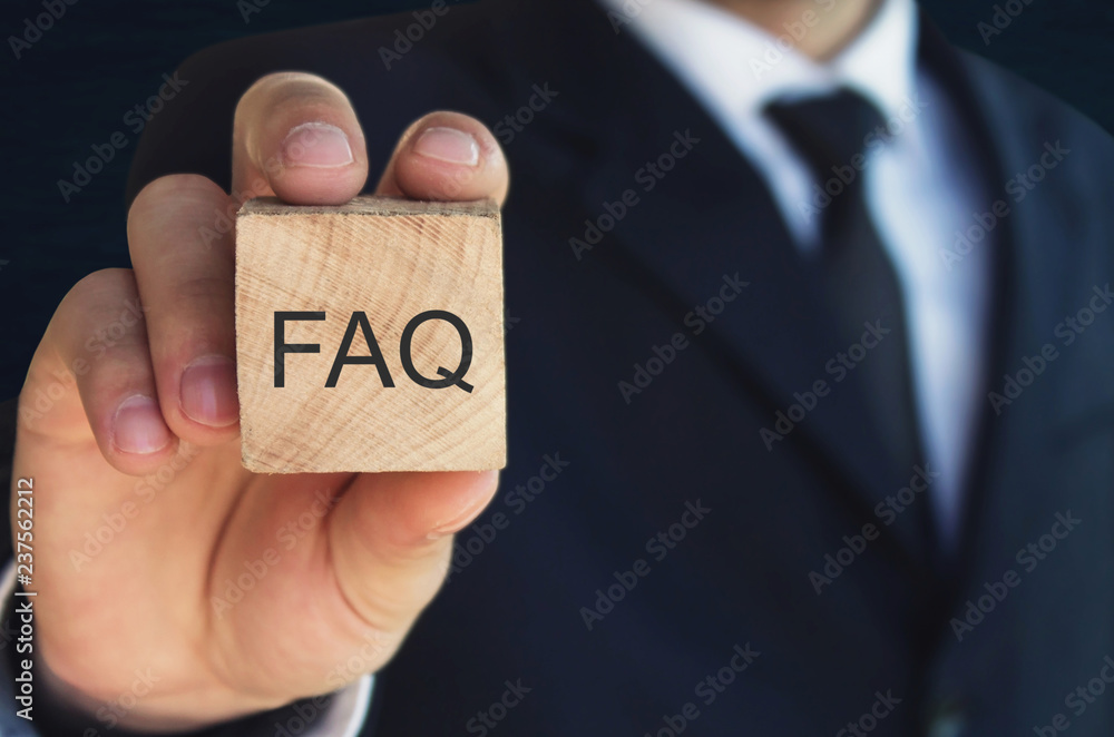 Man holding FAQ message on wooden cube. Frequently Asked Questions - obrazy, fototapety, plakaty 