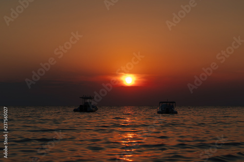 Beautiful sunset. In the distance you can see two small boats. © teksomolika