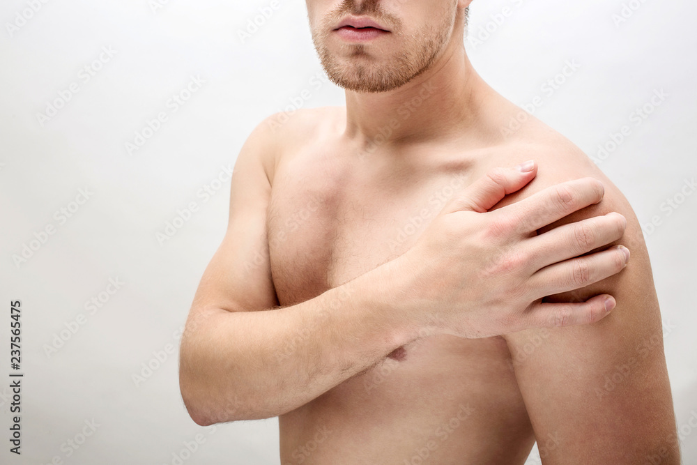 Cut view. Young man hold hand on shoulder. He feels pain there. Isolated on white background. Cut view. Young man hold hand on shoulder. He feels pain there. Isolated on white background.