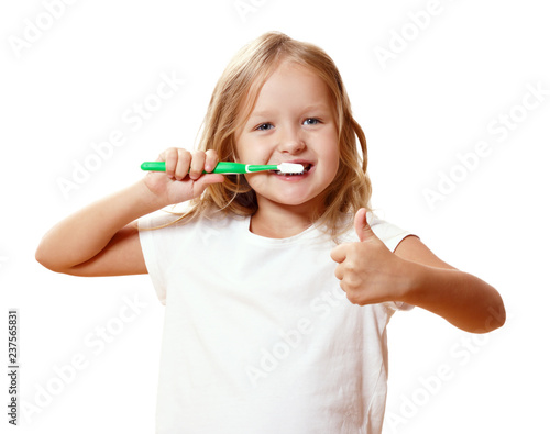 A little kid girl is brushing her teeth with a toothbrush. The concept of daily hygiene. Isolated on white background