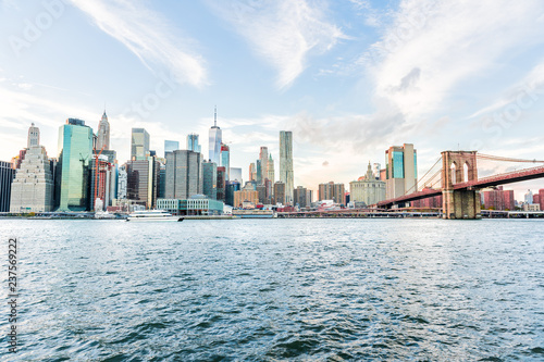 View of outside outdoors in NYC New York City Brooklyn Bridge Park by east river  cityscape skyline at day sunset  skyscrapers  buildings  tour boat