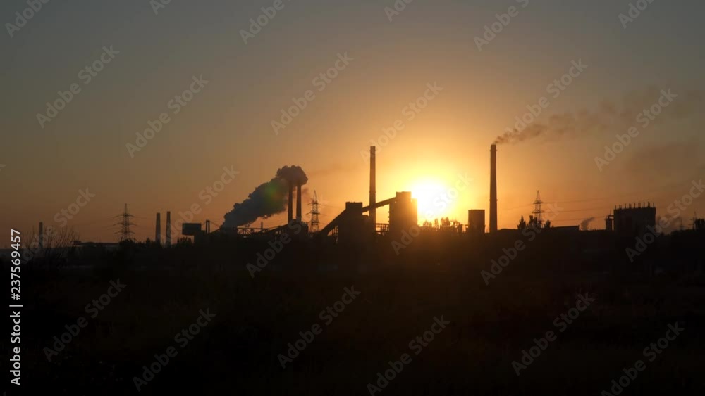 Environmental pollution. Smoke from the pipes of the metallurgical plant on the background of the rising sun
