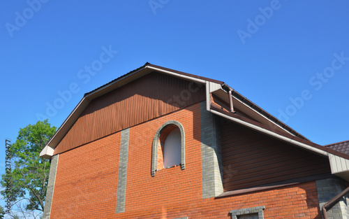Photography House mansard roof with brick wall, unfinished window installation,  rain gutters