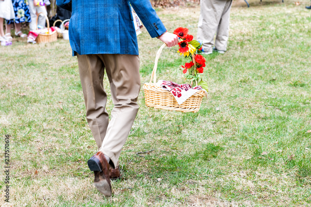 Man back walking, holding Easter blessing basket, flowers, embroided, embroidery towel, people outside church