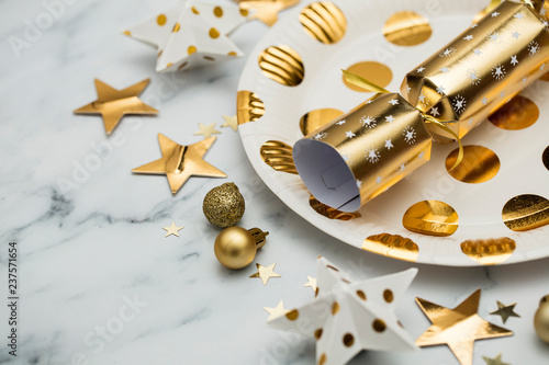 Festive Christmas party place setting with gold plate, cracker and decorations