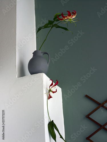 Blumen Stillife mit zwei Blumen auf Wand Sims vor grüner Wand photo