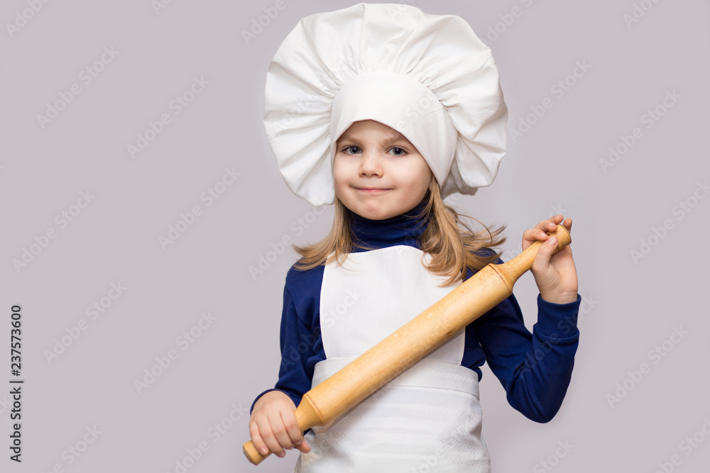 Children cook. Happy little girl in chef uniform holds rolling pin isolated on white background. Children cook. Happy little girl in chef uniform holds rolling pin isolated on white background.