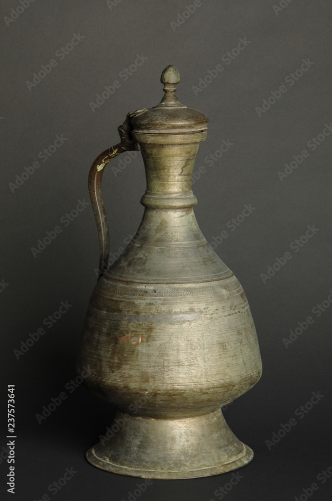 ancient oriental metal jug on dark background. antique bronze tableware ancient oriental metal jug on dark background. antique bronze tableware