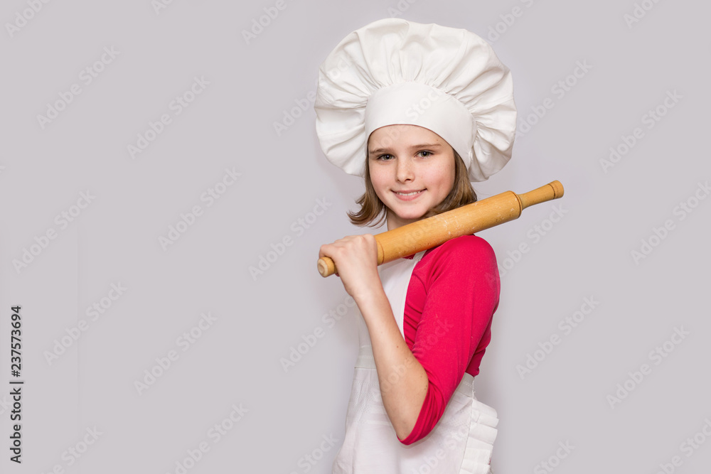 Children cook. Happy little girl in chef uniform holds rolling pin isolated on white background. Children cook. Happy little girl in chef uniform holds rolling pin isolated on white background.