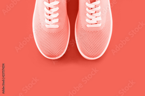 Trend photography on the theme of the actual colors for this season - a shade of orange. Bright orange sneakers on an orange background.
