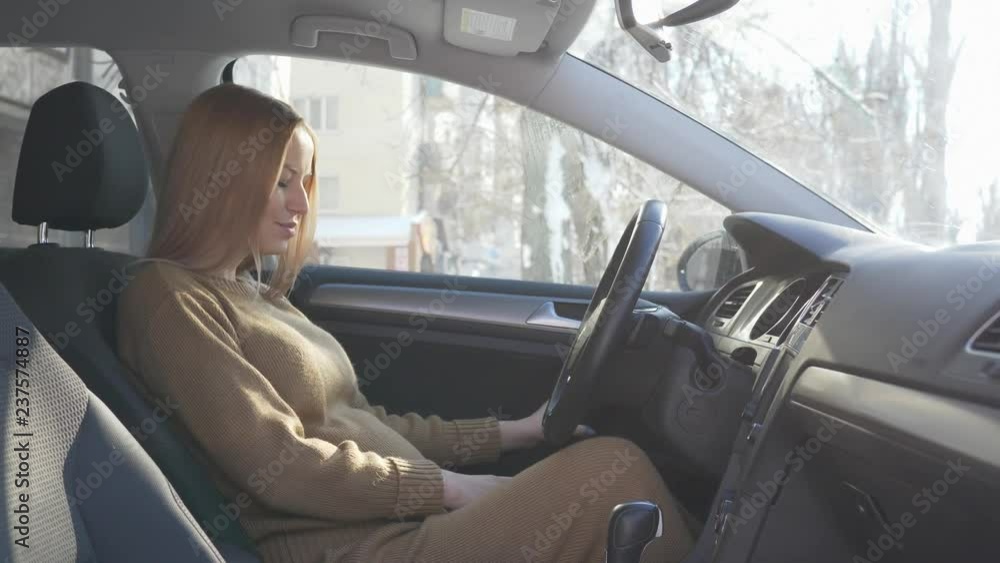 beautiful future mum closes the machine door then puts on the seat belt and stroking her big tummy in sunny day beautiful future mum closes the machine door then puts on the seat belt and stroking her big tummy in sunny day