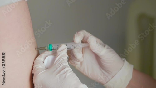 Close-up of the hand of a medic administering an intramuscular injection to a patient.