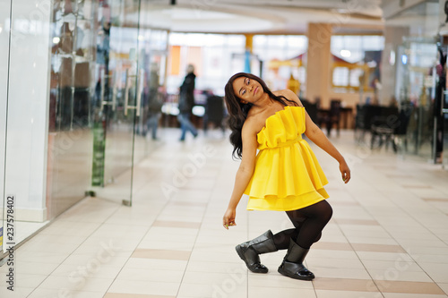 Stylish african american woman at yellow dreess posed at mall.