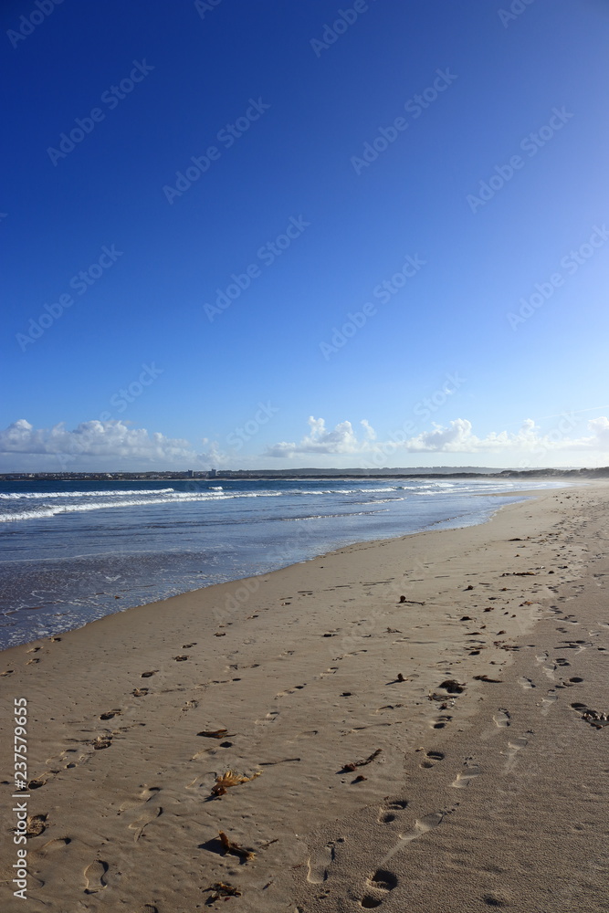 footprints in the sand of the beach with blue sky in the background