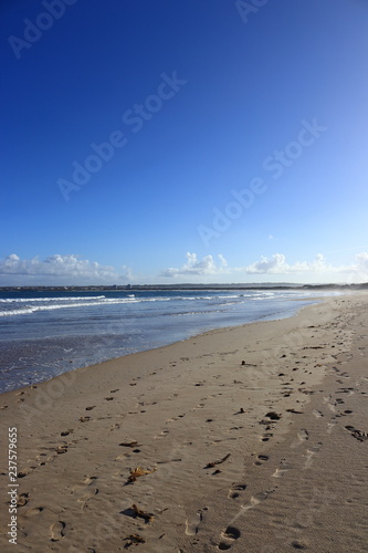 footprints in the sand of the beach with blue sky in the background