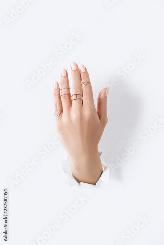 cropped image of woman showing hand with beautiful luxury silver rings through white paper