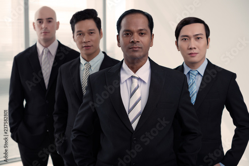 Portrait of successful multi-ethnic business team in suits looking at camera