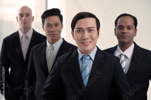 Smiling young VIetnamese businessman at the head of international business team