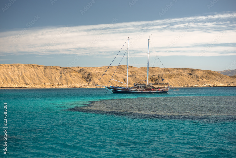 Obraz premium Sail boat in the coral sea near island. Summer vacation in an exotic country.