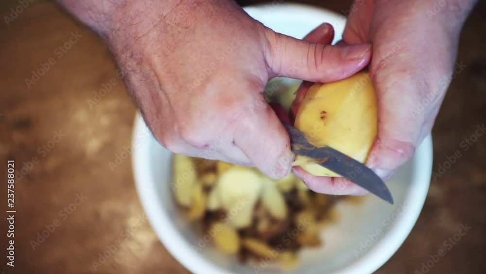 hands peeling raw potatoes with a knife.close-up.view from above. hands peeling raw potatoes with a knife.close-up.view from above.