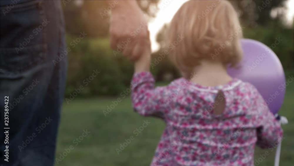 Close-up of hands of a young father and little daughter go to sunset side holding hands Close-up of hands of a young father and little daughter go to sunset side holding hands