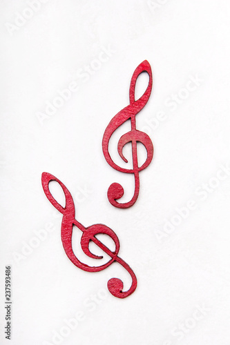 Red wooden treble clef on white background photo