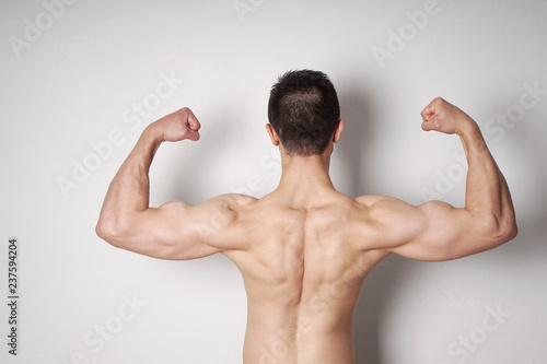 Obraz na plátně shirtless young man flexing biceps and back muscles