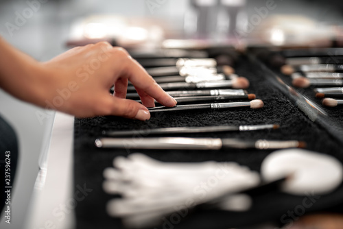Makeup artist is taking professional brush for applying shadows with natural pile