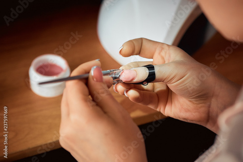 applying gel nail Polish, the woman doing the manicure