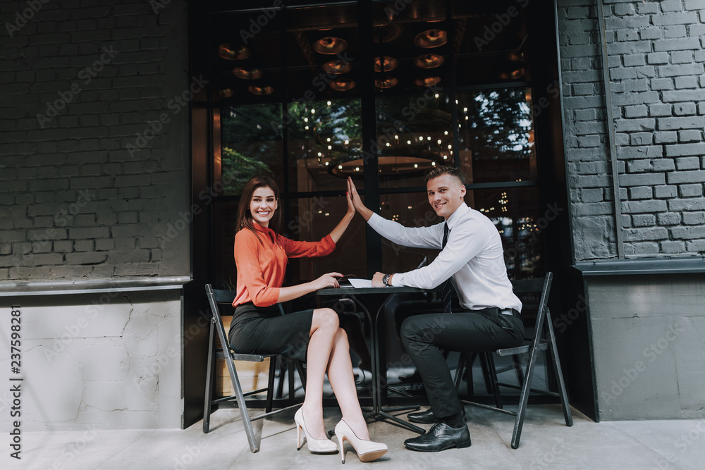 Have deal on business meeting. Full length portrait of office man and woman giving five together in outdoor cafe after successful work agreement
