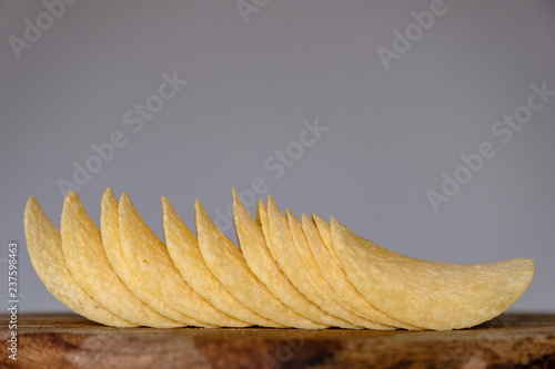Bunch of salty crisps presented on a wooden board, grey background photo